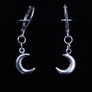 May include: A pair of silver crescent moon dangle earrings with a silver clip-on closure.