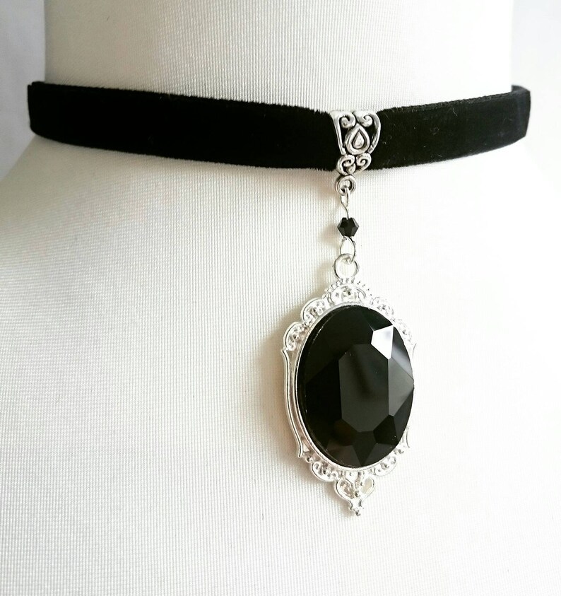 May include: A black velvet choker necklace with a silver pendant featuring a large black faceted gemstone.