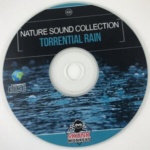 May include: A compact disc with a blue and black design featuring a picture of raindrops falling on water. The text "NATURE SOUND COLLECTION TORRENTIAL RAIN" is printed on the disc. The disc is labeled "COMPACT disc" and has the logo "SKUNK MONKEYS" printed on the bottom.