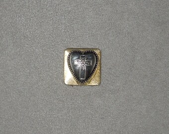 May include: A gold-colored heart-shaped charm with a black cross design inside. The charm has a textured border.
