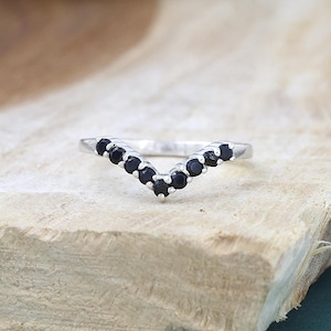 May include: A silver ring with a V-shaped band of black gemstones.