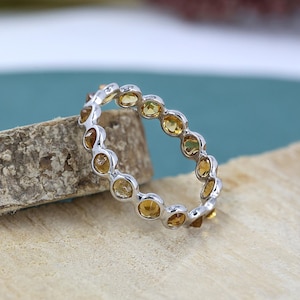 Peut inclure: Une bague en argent avec une rangée de pierres jaunes rondes serties.