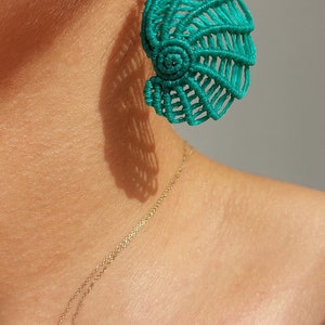 May include: Teal blue crocheted shell-shaped earrings with a gold hook.
