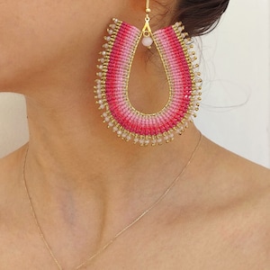 Peut inclure: Une paire de grandes boucles d'oreilles créoles en perles roses et blanches avec un crochet en métal doré. Les boucles d'oreilles sont dégradées, le rose passant au blanc.