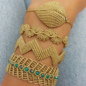 Könnte beinhalten: Vier goldene Freundschaftsarmbänder mit komplizierten Knotendesigns. Das untere Armband hat grüne Edelstein-Akzente.