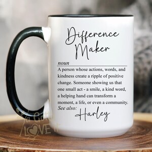 May include: White ceramic mug with a black handle and rim, featuring the text "Difference Maker" and a definition. The mug includes the name "Harley" and is displayed on a wooden surface. The mug is 15oz.