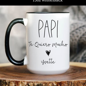 May include: White ceramic mug with a black handle and rim. The mug has black text that reads "Papi Te Quiero Mucho" with a heart symbol and the name "Yvette".