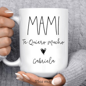May include: White ceramic mug with black text that reads "Mami Te Quiero Mucho" with a heart and the name "Gabriela" below. The mug is 15 oz.