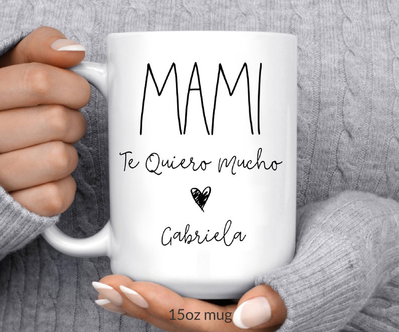May include: White ceramic mug with black text that reads "Mami Te Quiero Mucho" with a heart and the name "Gabriela" below. The mug is 15 oz.
