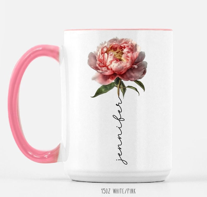 May include: White ceramic mug with a pink rim and handle. The mug features a pink peony flower with green leaves and the word "jennifer" written vertically in black script.