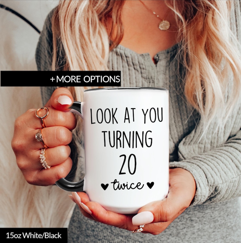 15oz white coffee mug with a black rim and handle. The mug has black text that reads 'Look at you turning 20 twice' with two black hearts on either side of the word 'twice'.