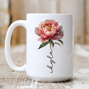May include: White ceramic mug with a pink peony flower and the name "Kyla" written in black cursive.