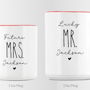 Puede incluir: Dos tazas de cer&aacute;mica blanca con asas y bordes rojos. La taza m&aacute;s peque&ntilde;a de 11oz tiene el texto negro Future MRS. Jackson con un peque&ntilde;o coraz&oacute;n. La taza m&aacute;s grande de 15oz tiene el texto negro Lucky MR. Jackson con un peque&ntilde;o coraz&oacute;n.