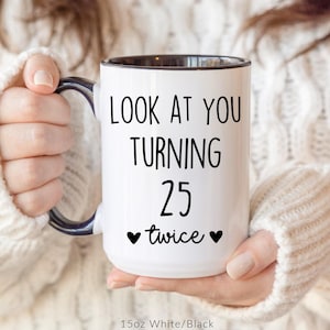 May include: White ceramic mug with black interior and handle. The mug features the text "LOOK AT YOU TURNING 25 twice" in black, with two black heart symbols. The mug is 15oz.