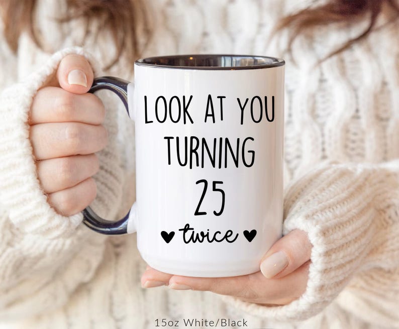 May include: White ceramic mug with black interior and handle. The mug features the text "LOOK AT YOU TURNING 25 twice" in black, with two black heart symbols. The mug is 15oz.
