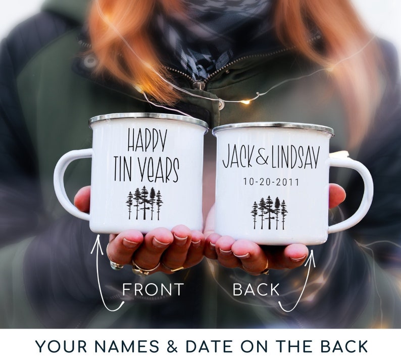 White enamel mug with black text and a forest design. The front mug says "Happy Tin Years" and the back mug is personalized with names and date.