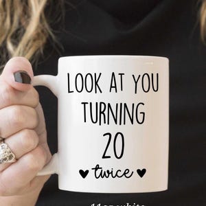 May include: White ceramic mug with the text "LOOK AT YOU TURNING 20 twice" in black. The mug has a capacity of 11oz. A fun gift for a milestone birthday.