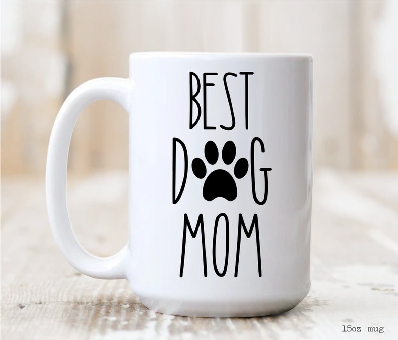 May include: White ceramic mug with a black paw print and the text "BEST DOG MOM" printed on it.