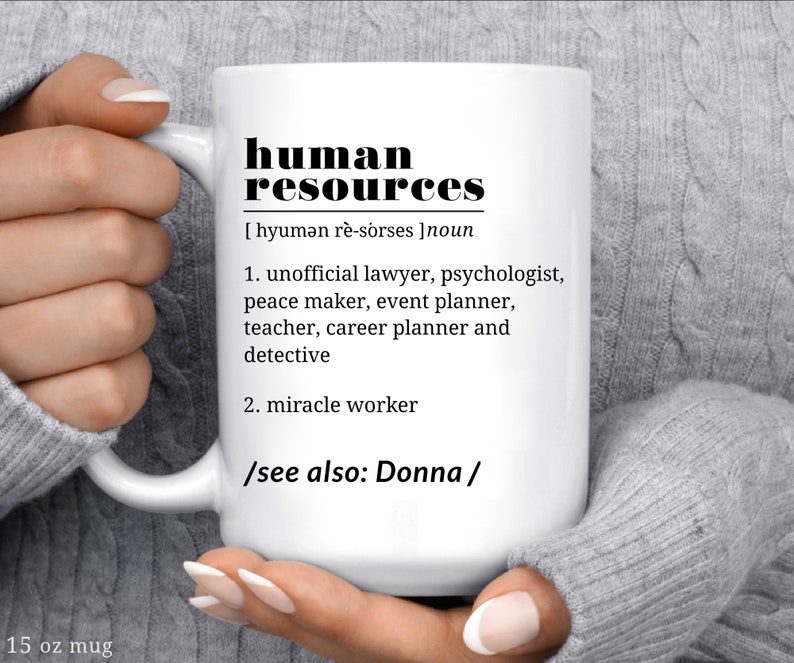 May include: White ceramic mug with black text that reads "human resources [hyumən r&egrave;-sorses] noun 1. unofficial lawyer, psychologist, peace maker, event planner, teacher, career planner and detective 2. miracle worker /see also: Donna/"