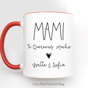 May include: White ceramic mug with a red rim and handle. The mug has black text that reads "MAMI Te Queremos Mucho" with a small heart and the names "Yvette & Sofia". The mug is labeled "11oz Red Accent Mug".