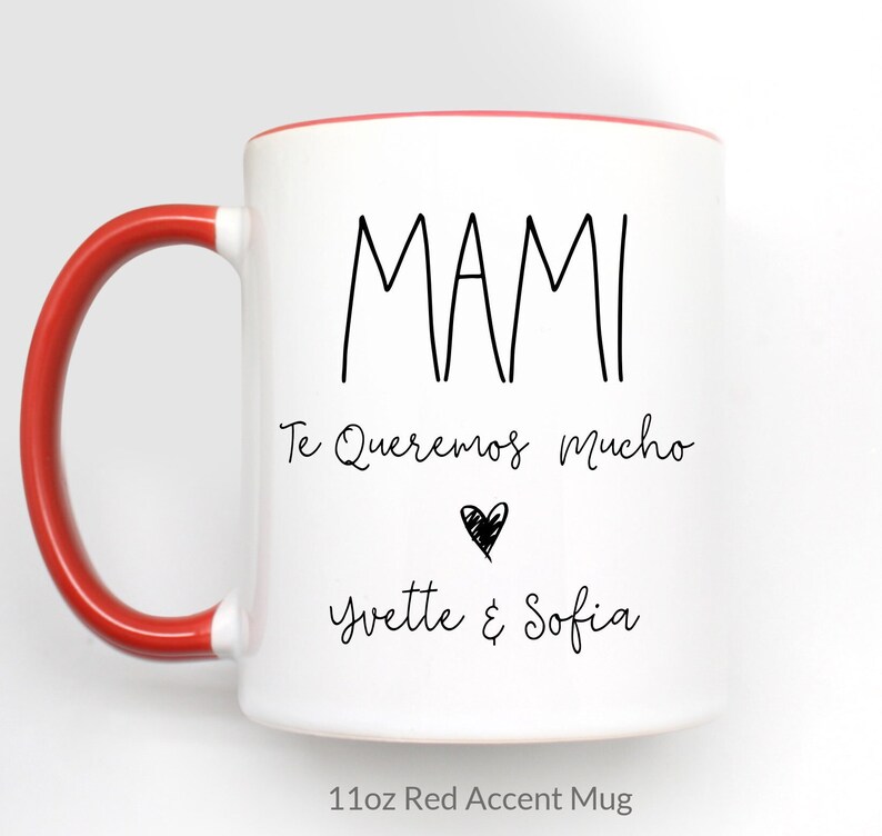 May include: White ceramic mug with a red rim and handle. The mug has black text that reads "MAMI Te Queremos Mucho" with a small heart and the names "Yvette & Sofia". The mug is labeled "11oz Red Accent Mug".