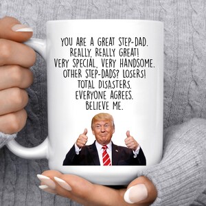 May include: White ceramic mug with a black and white image of Donald Trump giving a thumbs up. The mug has the text "You are a great step-dad. Really, really great! Very special, very handsome. Other step-dads? Losers! Total disasters. Everyone agrees. Believe me."