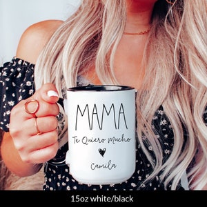 May include: White ceramic mug with a black rim and handle. The mug has black text that reads "MAMA Te Quiero Mucho" with a black heart and the name "Camila" underneath.