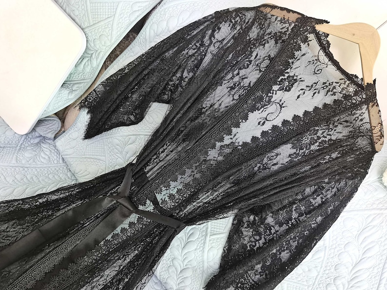 May include: Black lace robe with a satin tie belt. The robe is sheer and has a floral pattern.