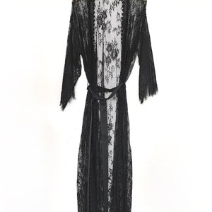May include: A black lace robe with a satin tie belt. The robe has a long, flowing silhouette and a delicate floral pattern.