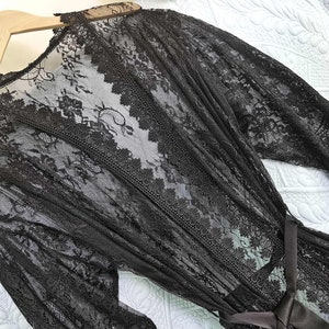 May include: Black lace robe with long sleeves and a tie belt. The robe is sheer and has a delicate floral pattern.