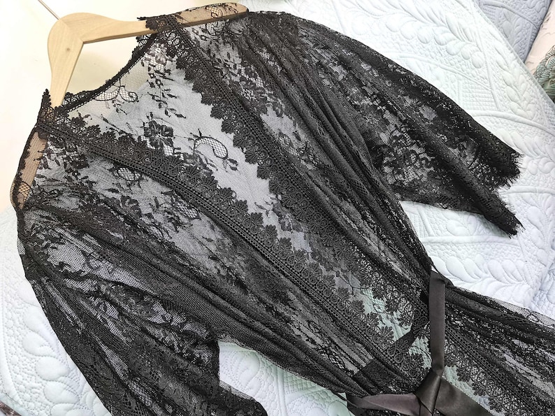 May include: Black lace robe with long sleeves and a tie belt. The robe is sheer and has a delicate floral pattern.