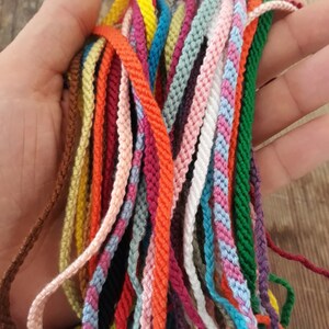 May include: A collection of colorful cords, including red, orange, yellow, green, blue, purple, pink, brown, black, and white. The cords are made of a soft, woven material and are perfect for crafting bracelets, necklaces, and other jewelry.