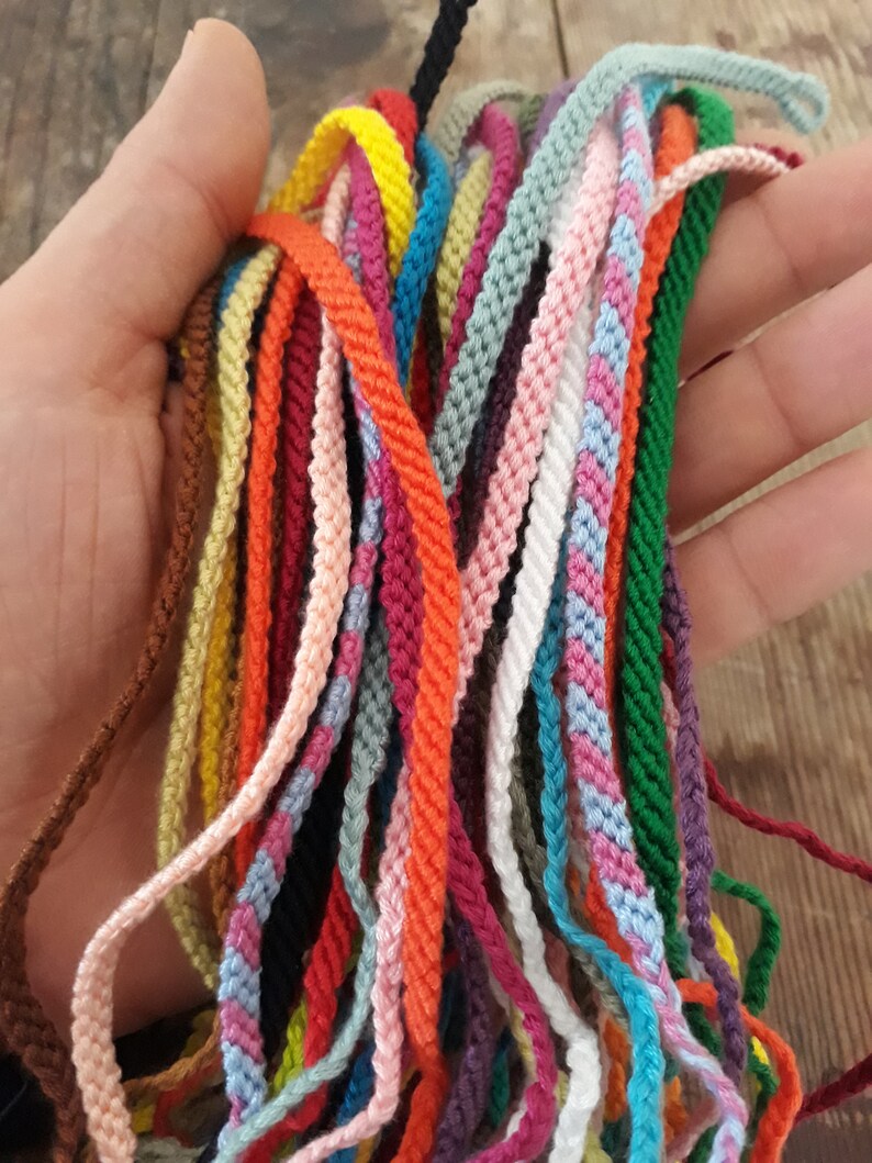 May include: A collection of colorful cords, including red, orange, yellow, green, blue, purple, pink, brown, black, and white. The cords are made of a soft, woven material and are perfect for crafting bracelets, necklaces, and other jewelry.
