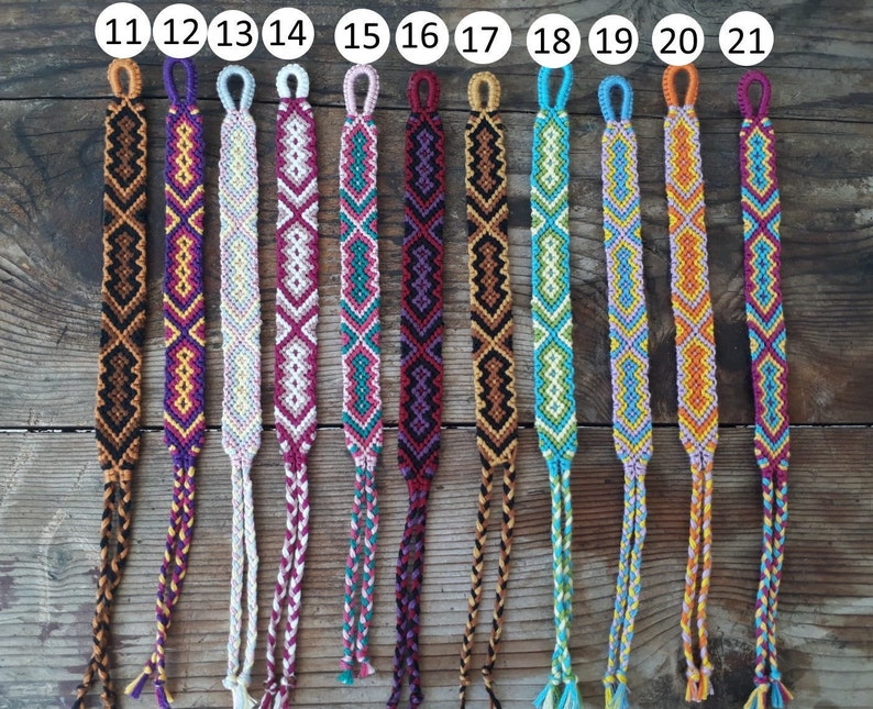 May include: A set of 11 colorful friendship bracelets with different geometric patterns. The bracelets are made with colorful embroidery floss and have a knotted fringe at the ends. The bracelets are numbered 11 through 21.
