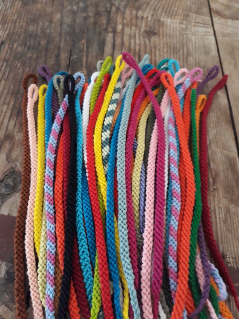 May include: A collection of colorful braided cords with loops at the end. The cords are arranged in a fan shape and are made of various colors, including red, blue, green, yellow, and pink.