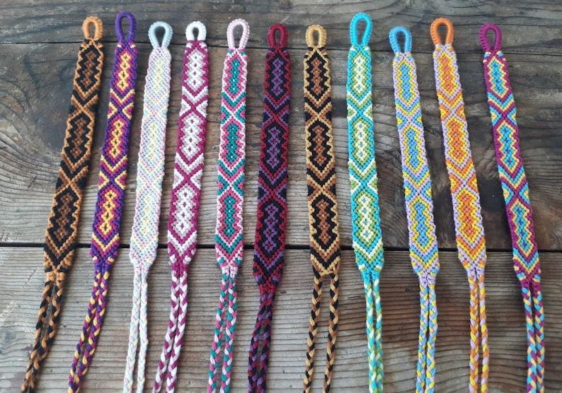 May include: Ten colorful friendship bracelets with different patterns and colors, including purple, pink, white, teal, brown, orange, and yellow.