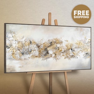 May include: Abstract painting on canvas with gold and white accents. The painting is framed and displayed on an easel.
