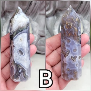May include: A polished hexagonal crystal tower featuring a translucent lavender and white agate base with intricate brown and gold-toned dendritic inclusions and small geode pockets throughout the stone, displayed in two different views labeled B.