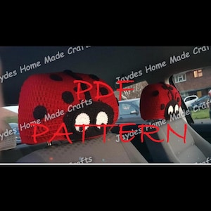 May include: Red and black crocheted ladybug headrest covers. The covers have a red base with black spots and white eyes. The headrests are in a car.