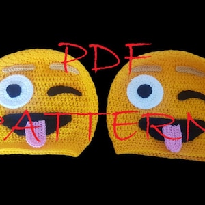 May include: Two yellow crocheted emoji hats with black mouths, pink tongues, and white and blue eyes. The hats have a winking eye and a straight-faced eye. The word "PDF PATTERN" is written in red across the image.