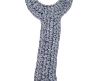 May include: A gray, crocheted dog toy shaped like a wishbone. The toy is made of a soft, textured yarn and has a loop at the bottom. The wishbone shape is perfect for dogs to chew and play with.
