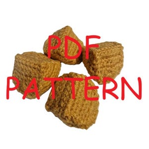 Pode incluir: Quatro pequenos cubos de crochê, texturizados, castanho-dourados, dispostos sobre um fundo branco. O texto vermelho "PDF PATTERN" é sobreposto aos cubos. Os cubos parecem ser feitos à mão e provavelmente fazem parte de um projeto artesanal.