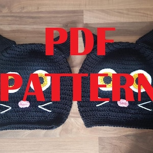 May include: Two black crochet cat hats with white, yellow, and pink facial features. The hats have pointed ears and are displayed on a wooden surface. The word "PATTERN" is overlaid in red.