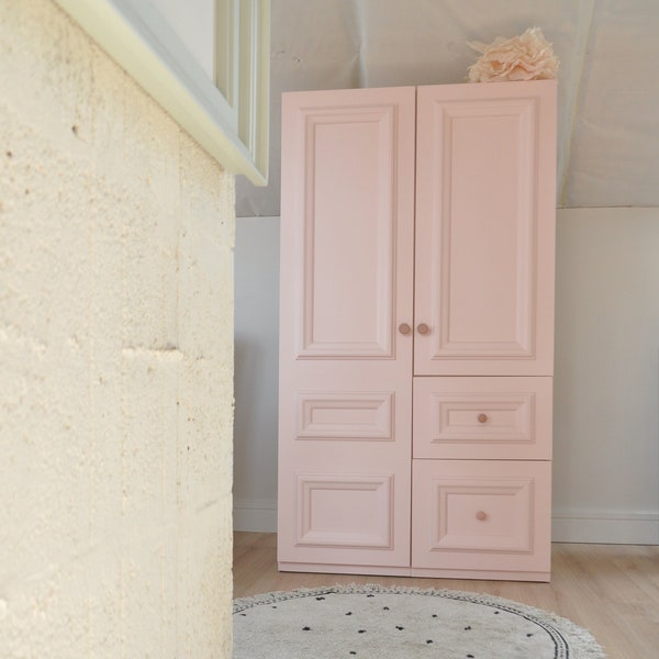 une armoire deux portes rose à tiroirs au style intemporel. Armoire enfant classique avec étagères et cintre Melody