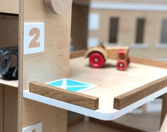 Houten parkeergarage speelgoed. Parkeerplaats in Montessori-stijl met glijbaan, tankstation, lift en slagbomen