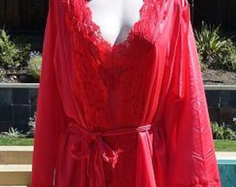 May include: A long, red robe with a V-neckline and lace trim, displayed on a mannequin. The robe features long sleeves with lace cuffs and a matching tie belt. The garment is made of a flowing fabric.