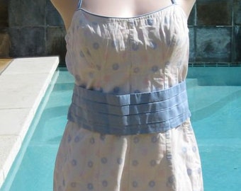 May include: A white halter-style swimsuit with a blue floral pattern and a blue ribbon around the waist.