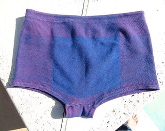 May include: A pair of blue and purple underwear. The underwear has a square blue panel in the center, with purple and red accents on the sides. The garment is made of a textured fabric.