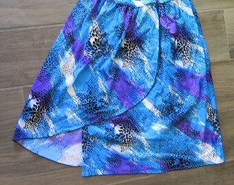 May include: A wrap skirt with a vibrant blue, purple, and white floral pattern. The skirt has a flowing design and is made of a lightweight fabric. The skirt's design includes a mix of abstract and floral elements.