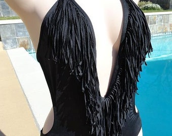 May include: Black one-piece swimsuit with a halter neck and fringe detailing. The swimsuit features a deep V-neckline and cut-out sides. The fringe adds a bohemian flair to the swimwear.